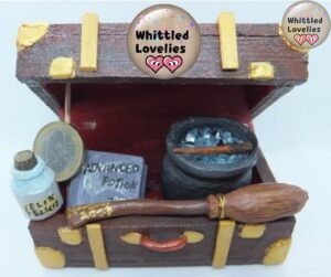Il baule di Harry Potter. Una valigia di legno con inserti in oro con all'interno una pozione felix felici, il libro delle pozioni, un calderone, una bacchetta, e la scopa Nimbus 2000, tutto realizzato in legno. Miniatura, gli oggetti sono più o meno della dimensione di una moneta.